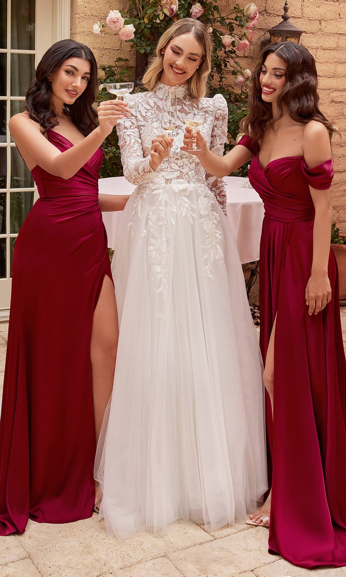 Three women stand outdoors, one in the Off-White Long Sleeve Lace Wedding Gown CDS433W and two in matching burgundy bridesmaid dresses, raising their glasses for a joyful toast.